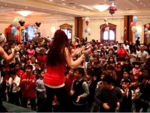 Dancing elves on stage in large room of kids