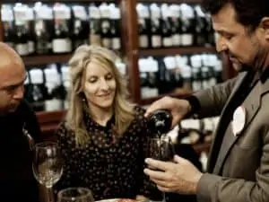 Man pouring wine with a woman and a man